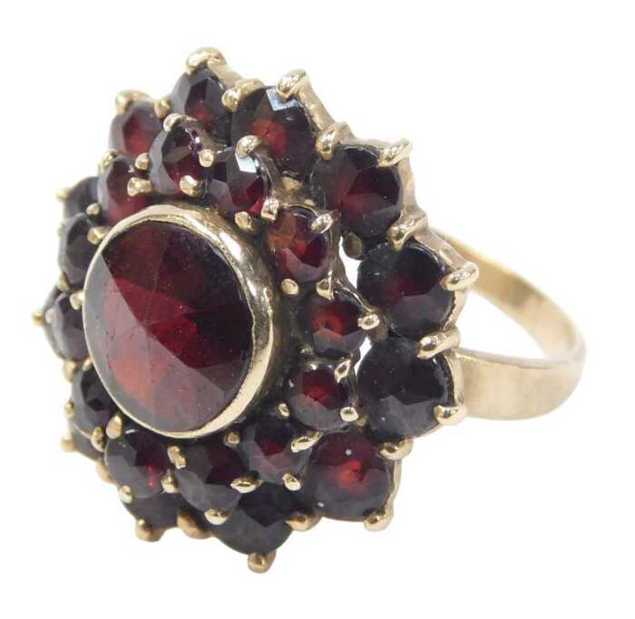 A 20thC garnet cluster ring, the central faceted garnet surrounded by twelve round brilliant cut...