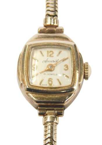 An Accurist 9ct gold cased lady's wristwatch, with a square cream numbered dial, on a 9ct gold...
