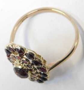 A 20thC garnet dress ring, the halo ring with a central cabochon-cut garnet, surrounded by rough-... - 2