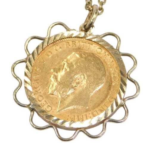 A George V gold half sovereign pendant and chain, dated 1914, in a 9ct gold waved frame, on a...