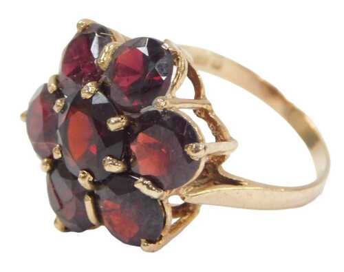 A 9ct gold garnet cluster ring, the raised shank set with seven round brilliant cut garnets, the...