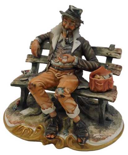A Capodimonte porcelain figure, modelled as a tramp on a bench, gilt heightened, printed marks,...