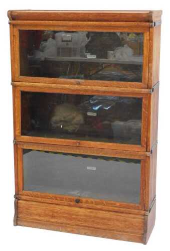 A Globe Wernicke oak three sectional bookcase, the top with a rounded edge above four glass...
