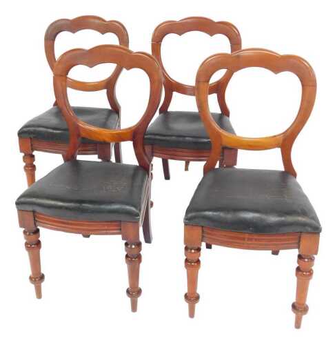 A set of four Victorian walnut balloon back chairs, each with a black leather overstuffed seat,...