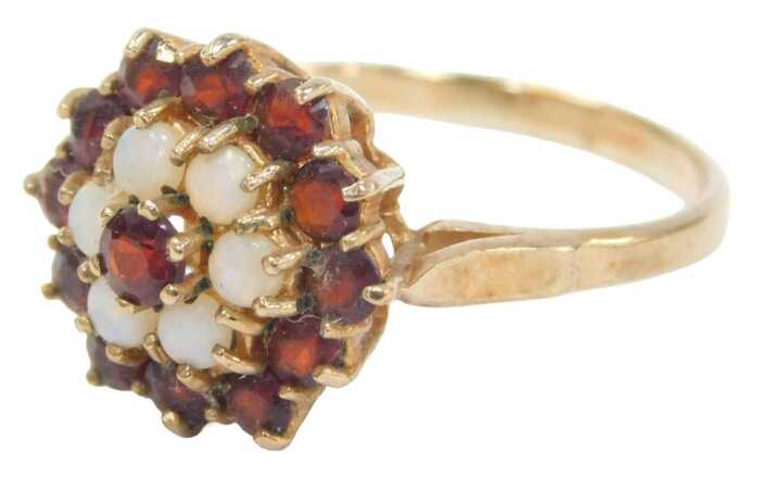 A 9ct gold cluster ring, set with garnets and opals, each concentric claw set in a raised basket,...
