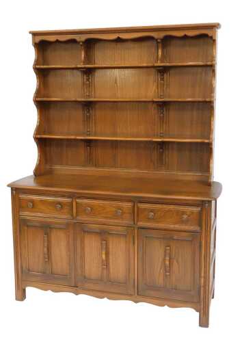 An Ercol Old Colonial elm dresser, the top with a four shelved plate rack, the base with a...