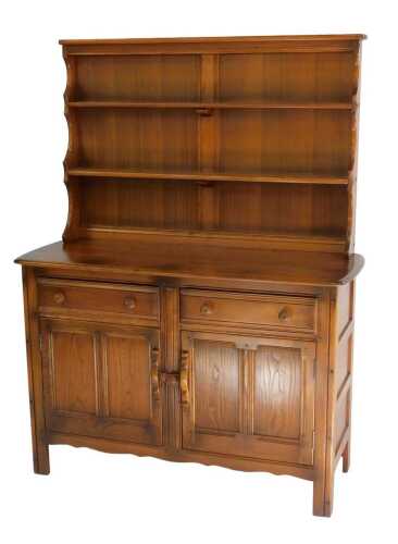 An Ercol Old Colonial elm sideboard, the top with a two shelved plate rack, the base with a...
