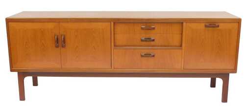 A 1970s G-Plan teak sideboard, with three central drawers flanked to one side by two cupboards,...
