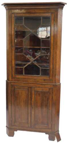 A Georgian oak standing corner cabinet, the top with a moulded edge above an astragal glazed...