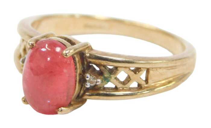 A 9ct gold and cabochon dress ring, the red cabochon in a raised basket with two tiny diamond...