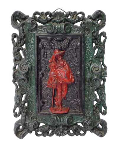 A painted cast iron wall plaque, decorated centrally with a figure of a musketeer in red, within...