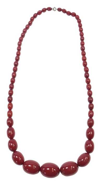 A graduated cherry amber necklace, of fifty seven beads, the largest 3.5cm wide, the smallest...