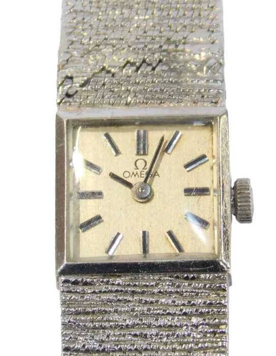 An Omega 9ct white gold lady's wristwatch, the silvered square watch head with baton dial, and...