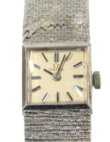 An Omega 9ct white gold lady's wristwatch, the silvered square watch head with baton dial, and...