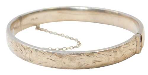 A Georg Jensen silver half-hinged bangle, the top with engraved floral decoration, with safety...