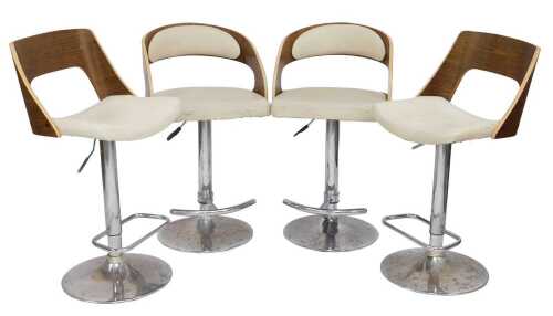 A harlequin set of four wooden veneer bar stools, each with a cream leatherette seat, raised on...