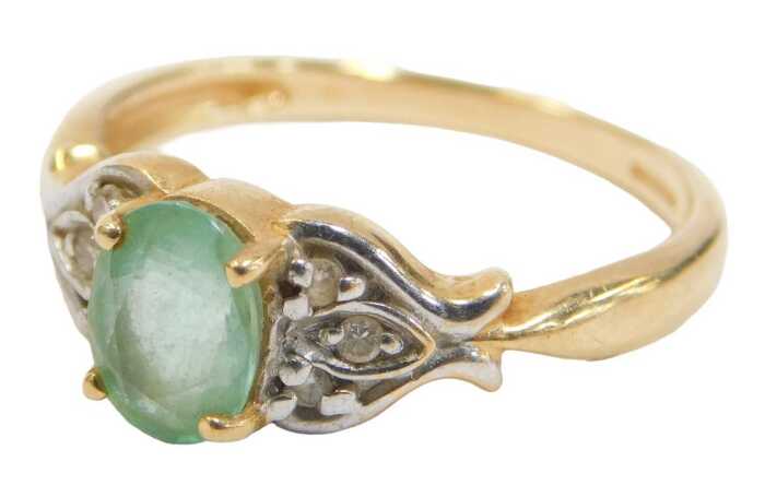 An 18ct gold emerald and diamond dress ring, the oval emerald in a four claw setting, with tiny...