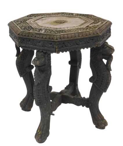 A Burmese carved ebonised hardwood table, the octagonal top carved with floral motifs, raised on...
