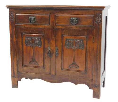 An Art Nouveau walnut sideboard, the top with a moulded edge above two drawers and two panelled...