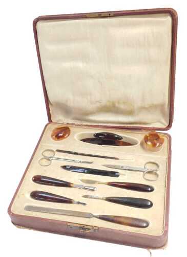 An early 20thC simulated tortoiseshell manicure set, contained in a fitted case, 25.5cm wide.