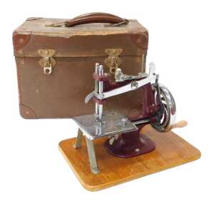 A mid century child's hand operated sewing machine, in purple, 20cm high, cased.