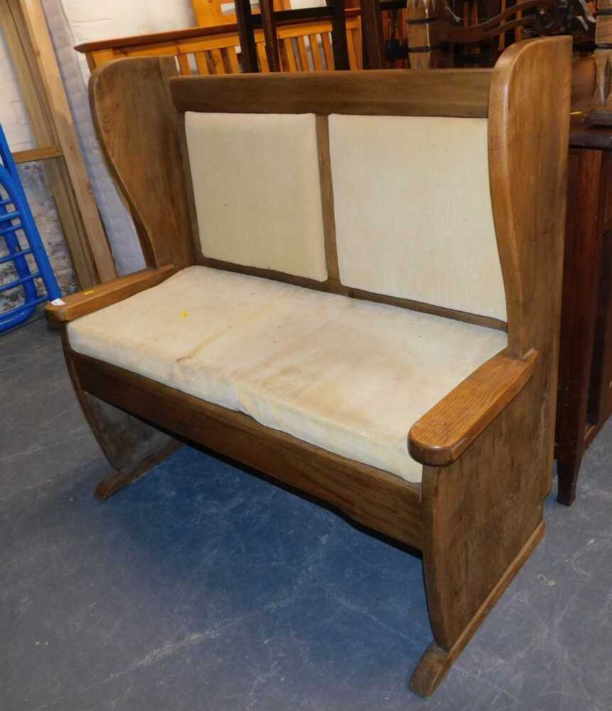 An oak settle, with overstuffed seat and back, 105cm wide.