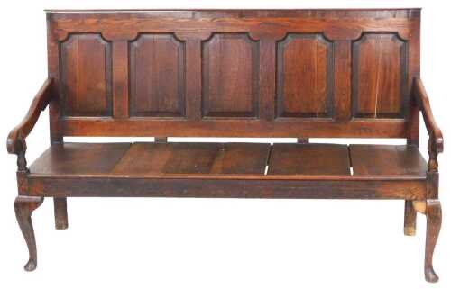 A George III oak settle, with a five panelled back, and solid seat, with outswept...