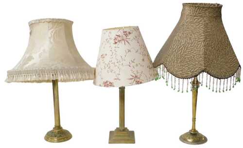 Three Edwardian and later brass tablelamps, with embossed or fluted decoration, with shades.