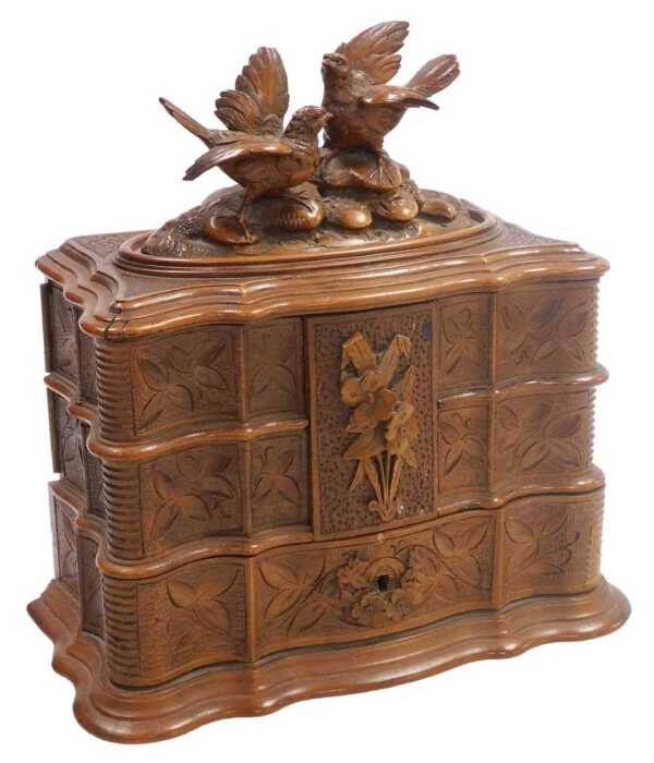 A late 19thC Black Forest wooden jewellery casket, the hinged lid carved with a pair of birds...