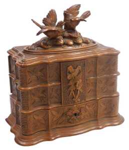 A late 19thC Black Forest wooden jewellery casket, the hinged lid carved with a pair of birds...