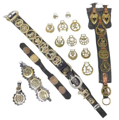 A group of 19thC and later horse brasses, mounted on martingales, a leather belt, etc.