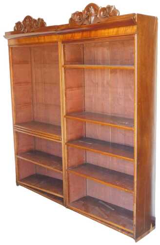 A pair of Victorian mahogany open bookcases, each with a fall and scroll carved pediment, above...
