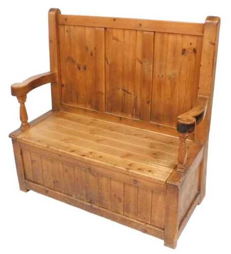 An early 20thC pine settle, with a triple panelled back, scrolling arms, above a base with a...