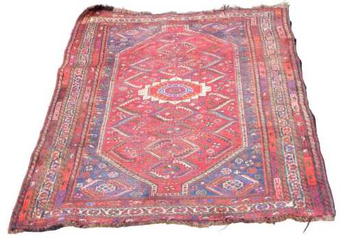 A Shiraz red ground rug, the central field with one large and eight small floral medallions,...