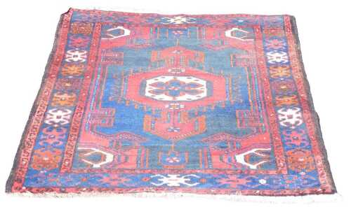 A Persian Shahsavan blue and red ground rug, with a central floral medallion, within repeating...