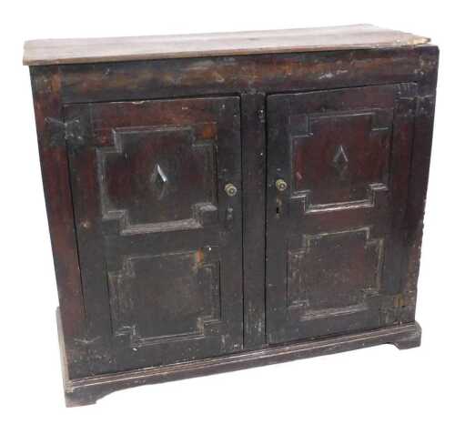 A late 17th/early 18thC oak cupboard, with a planked top above two panelled doors, with brass...