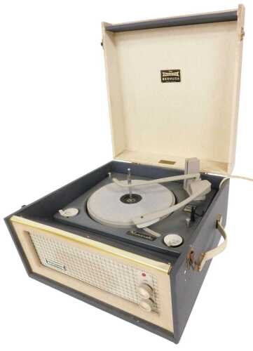 A vintage Dansette record player, in a cream and grey canvas case, the underside with mounts for...