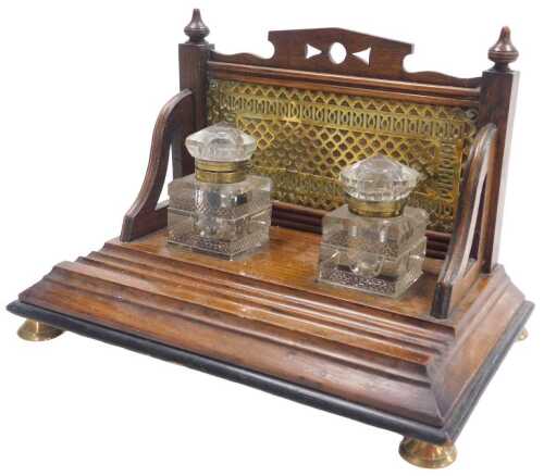 A Victorian oak and ebonised desk stand, the raised back with Gothic style brass plaque, the...
