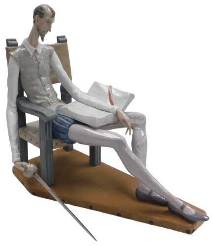A large Lladro porcelain figure of Don Quixote, modelled seated on a chair with a book, whilst...