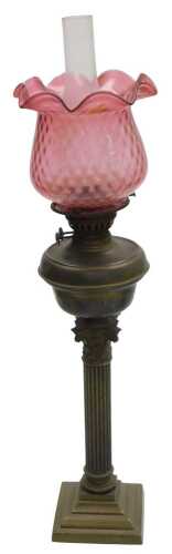 A brass Corinthian column oil lamp, with a cranberry tinted shade, 81cm high.