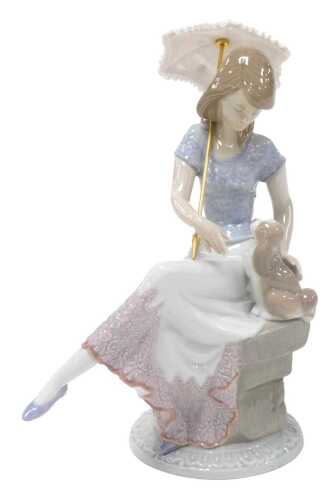 A Lladro porcelain figure of a girl, seated on a plinth, beside a puppy, Lladro Collector's...