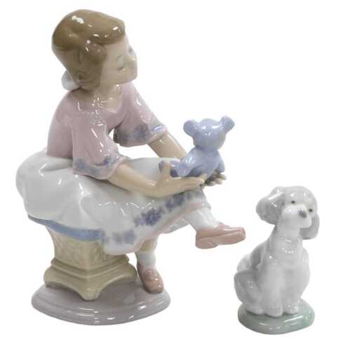 A Lladro porcelain figure of a girl seated on a pouffe, holding a Teddy bear, Collector's...