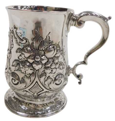A George III silver tankard, with a double scroll handle, and later embossed decoration of...
