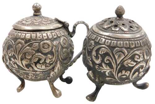 An early 20thC Indian mustard pot and pepperette, of spherical form, with embossed foliate...