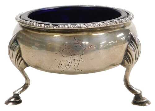 A George III silver salt, of circular form, with a Bristol blue glass liner, raised on three...