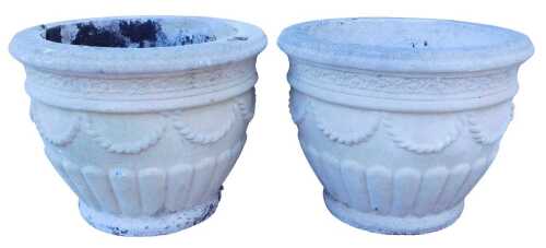 A pair of composition stone garden jardinieres, each decorated with swags, and with part fluted...