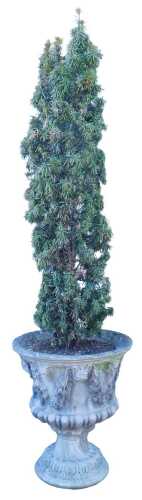 A composition stone garden urn, decorated with masks, swags of leaves and berries, on a leaf...