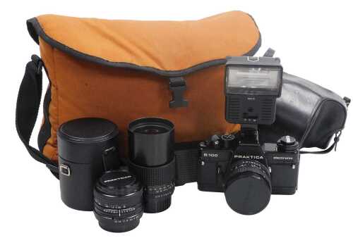 A Praktica B100 electronic camera, flash, additional lens, etc., in a carrier bag.