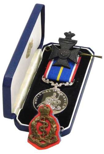 A National Service Medal, no. 81693, cased, together with a Royal Army Medical Corps cap badge,...