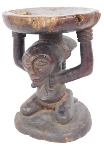 A Congolese Songye tribal stool, with circular top supported by a kneeling male figure, on a...